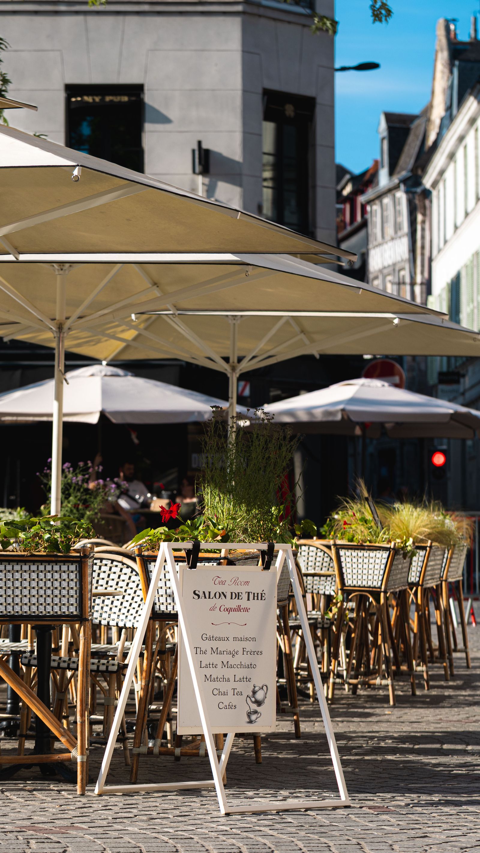 La terrasse pavée de Coquillette sous les parasols, avec le chevalet Tea Room — Salon de thé, place du Vieux-Marché à Rouen